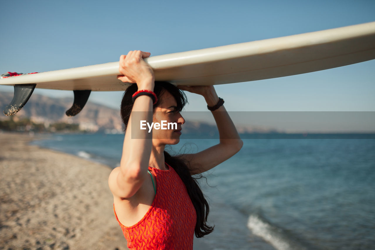 Woman standing at beach against sky