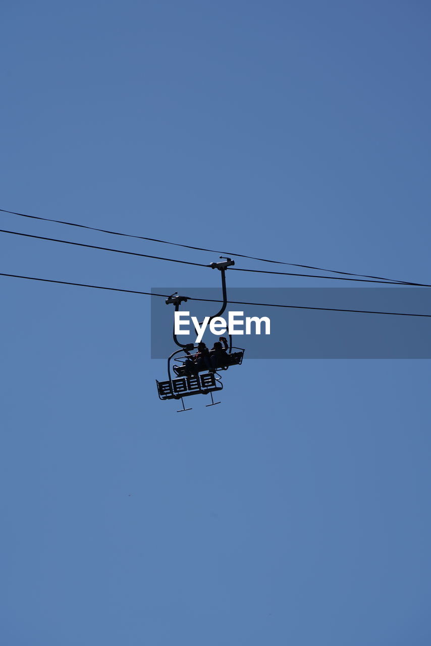 LOW ANGLE VIEW OF OVERHEAD CABLE CAR AGAINST BLUE SKY