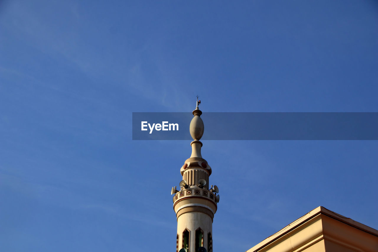 Low angle view of mosque tower against blue sky