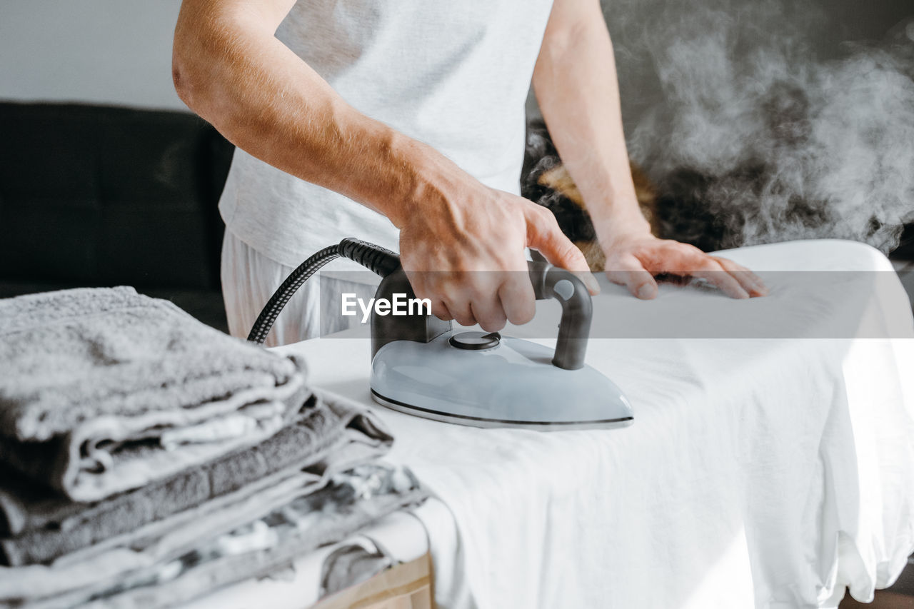 Midsection of man ironing clothes at home