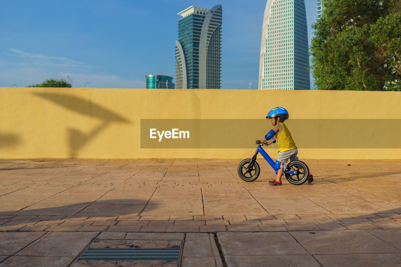 Side view of boy cycling on footpath