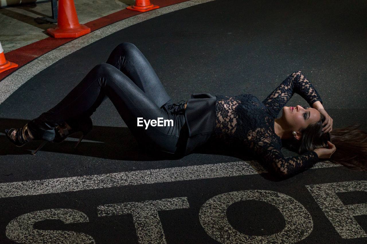 High angle view of woman lying road with stop text 