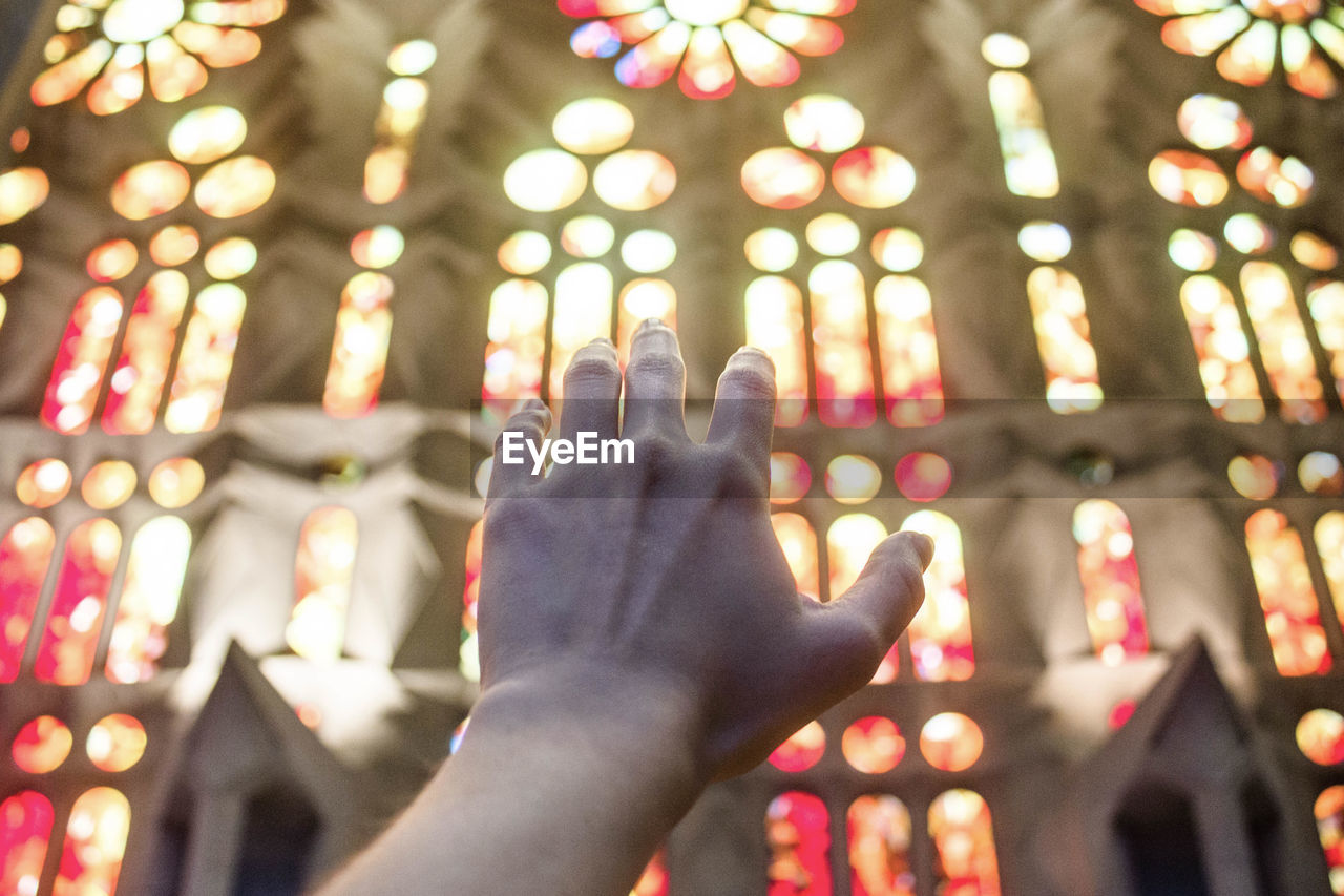 Close-up of hand against stained glass windows in church