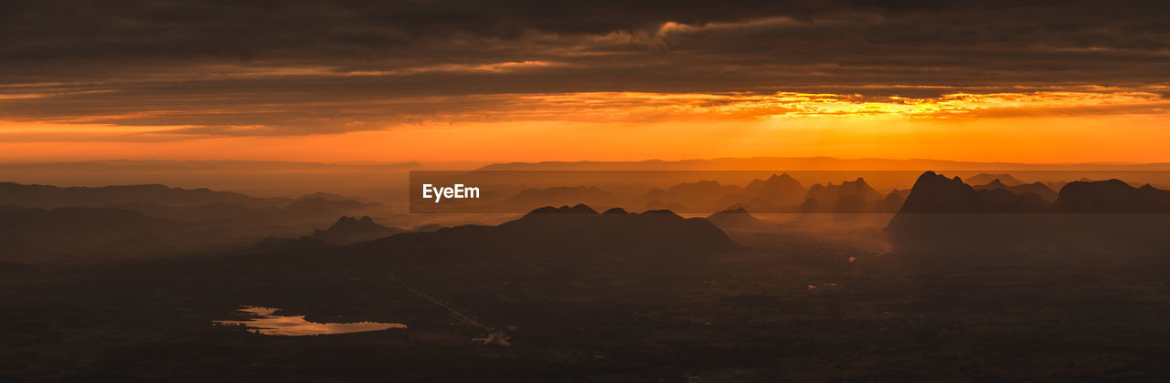 Scenic view of silhouette mountains against orange sky