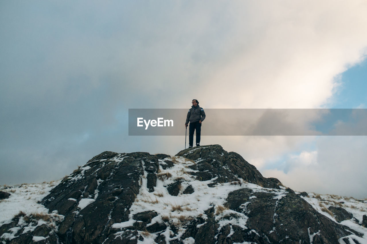 Low angle view of young woman standing on mountain peak