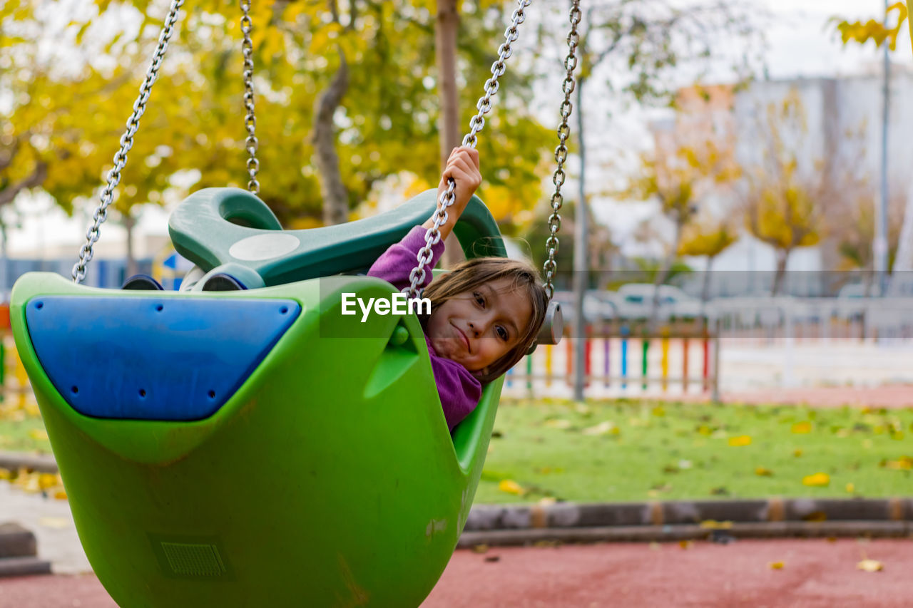 Close-up of girl on swing in playground