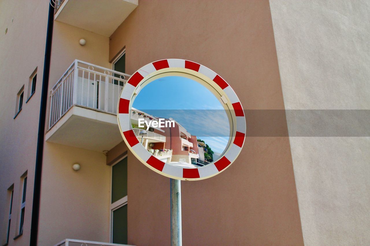 Low angle view of mirror against buildings in city