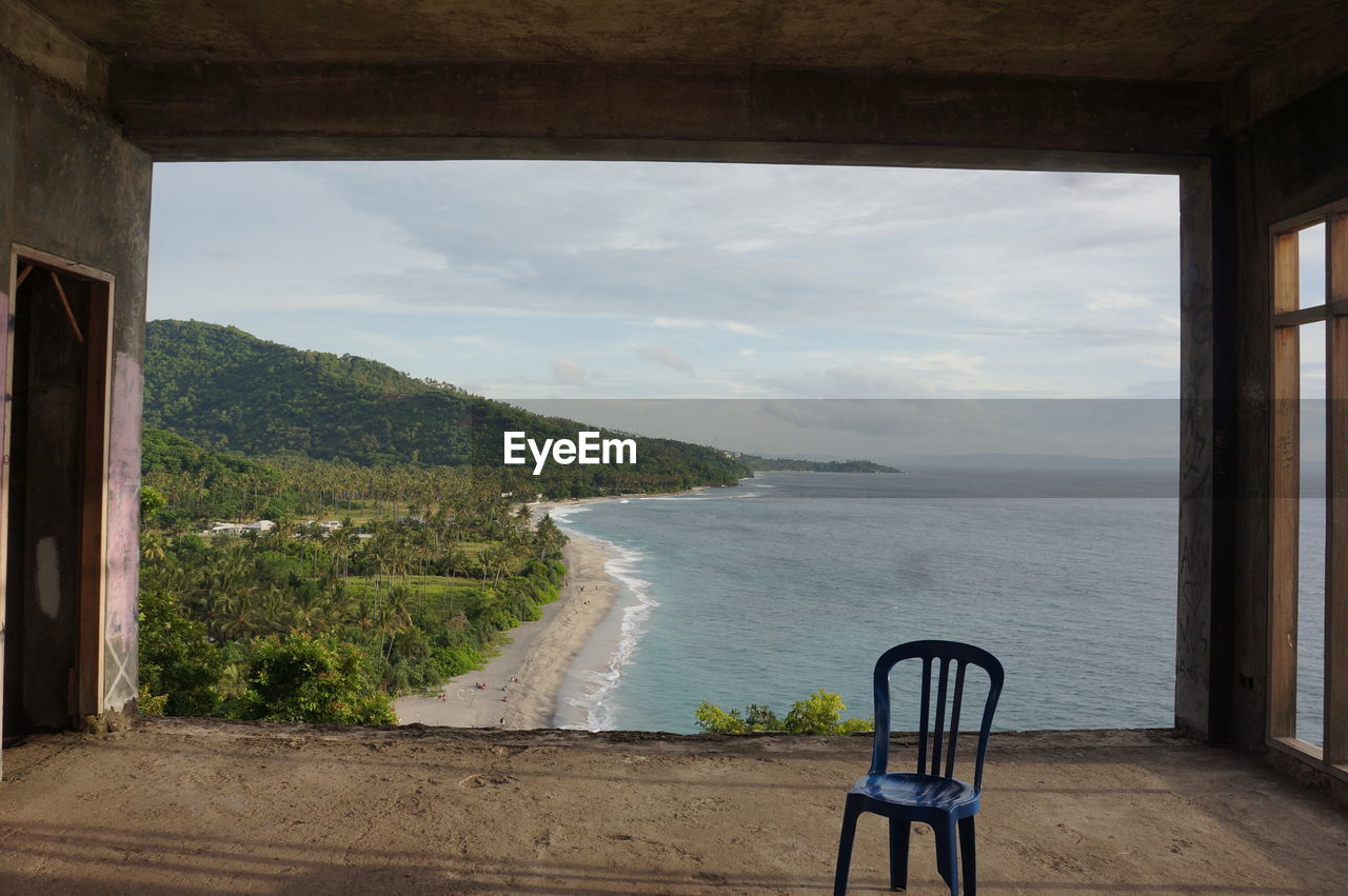 Chair at abandoned building against sea 