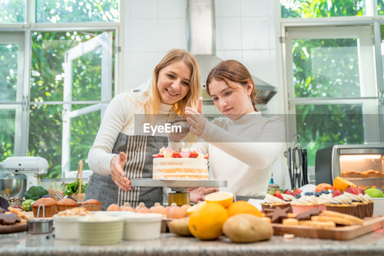 Mother and daughter working together happily to make sweets on holiday.