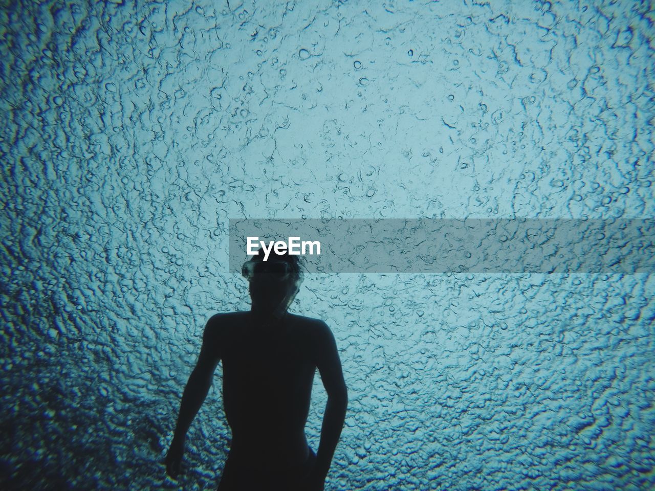 Silhouette teenage boy swimming in sea