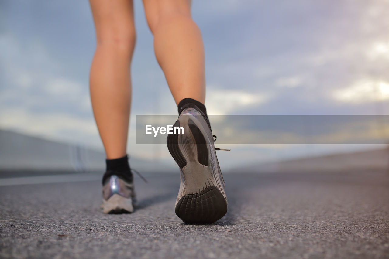 Female sport runner getting ready for jogging outdoors on  the city road.