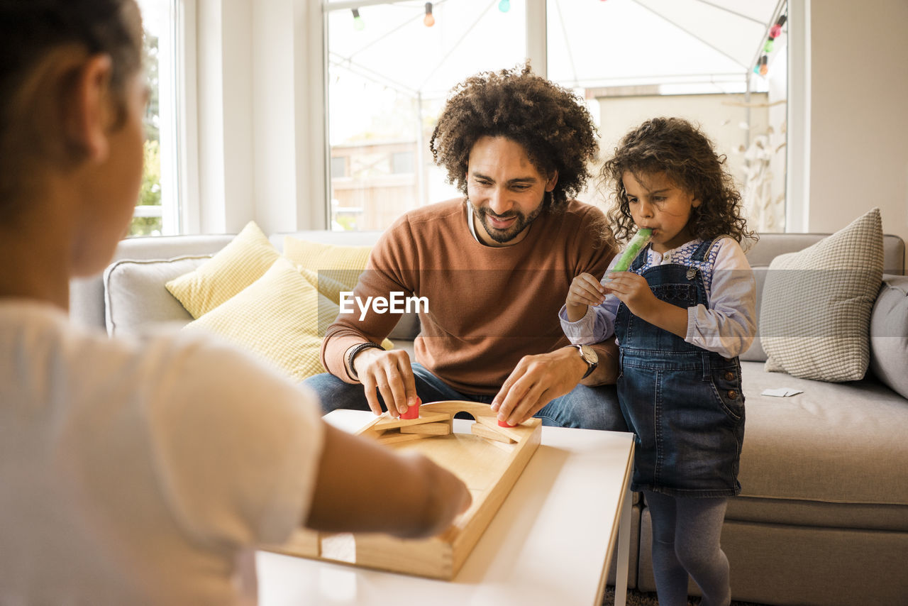 Smiling father playing board games with daughters at home