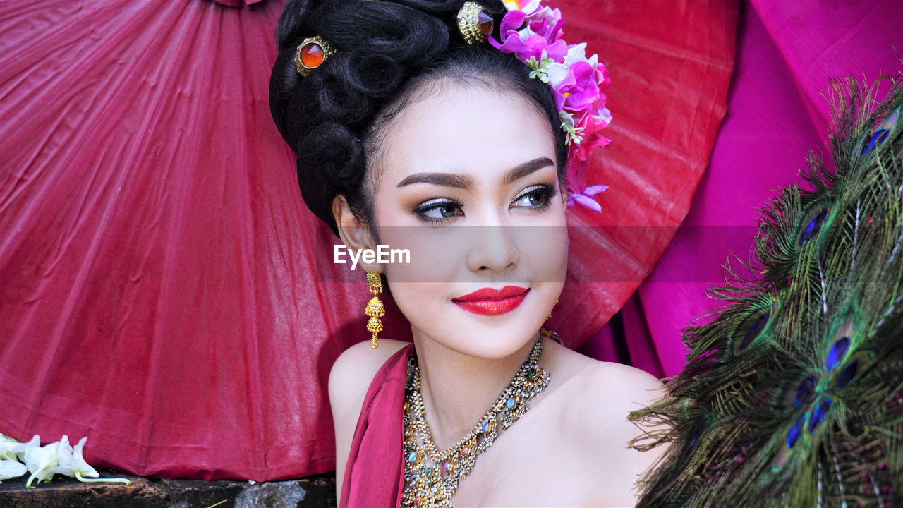 PORTRAIT OF YOUNG WOMAN WITH FLOWERS IN BACKGROUND