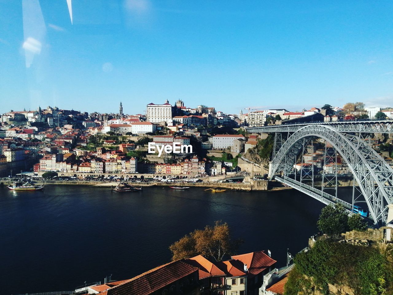 BRIDGE OVER RIVER BY BUILDINGS AGAINST SKY