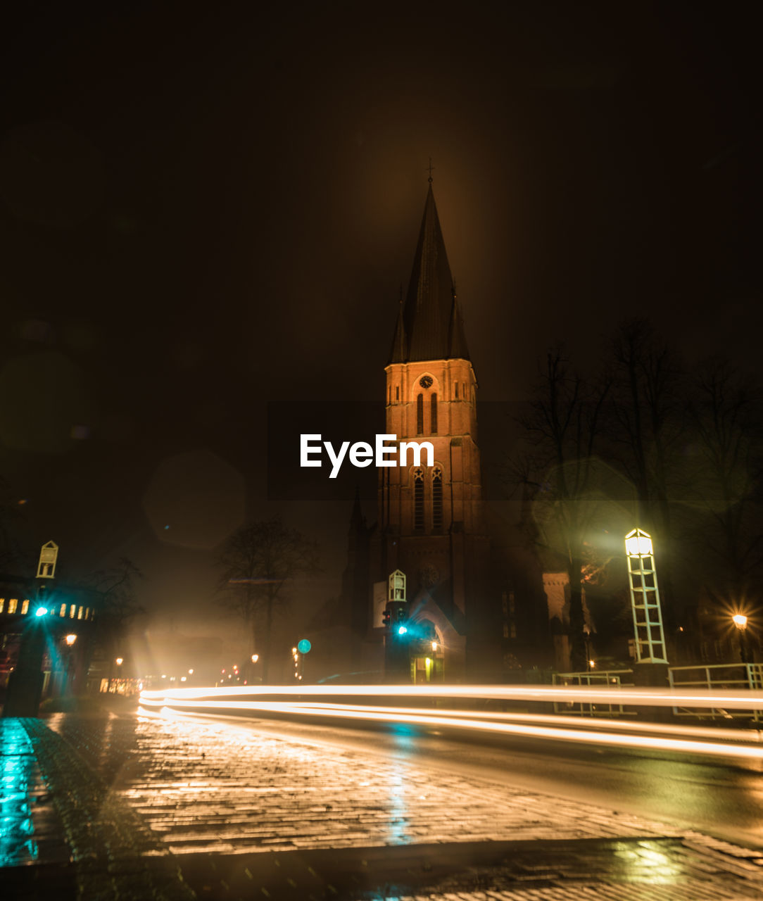 LIGHT TRAILS ON STREET AGAINST ILLUMINATED BUILDINGS AT NIGHT