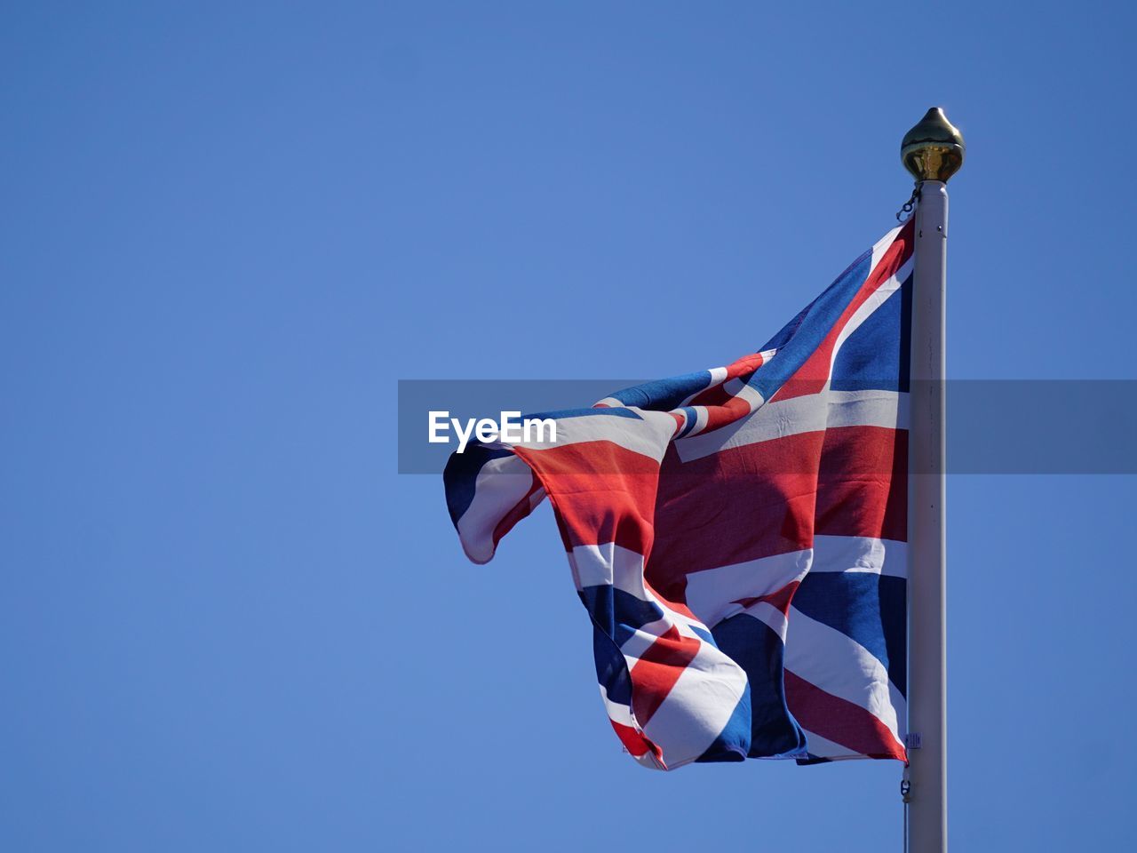 Low angle view of british flag against waving against clear blue sky