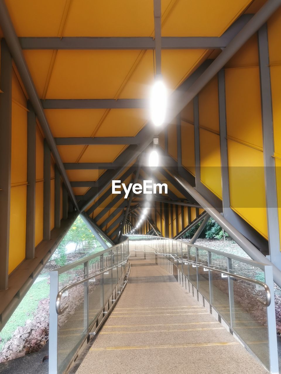 EMPTY FOOTBRIDGE IN ILLUMINATED CORRIDOR