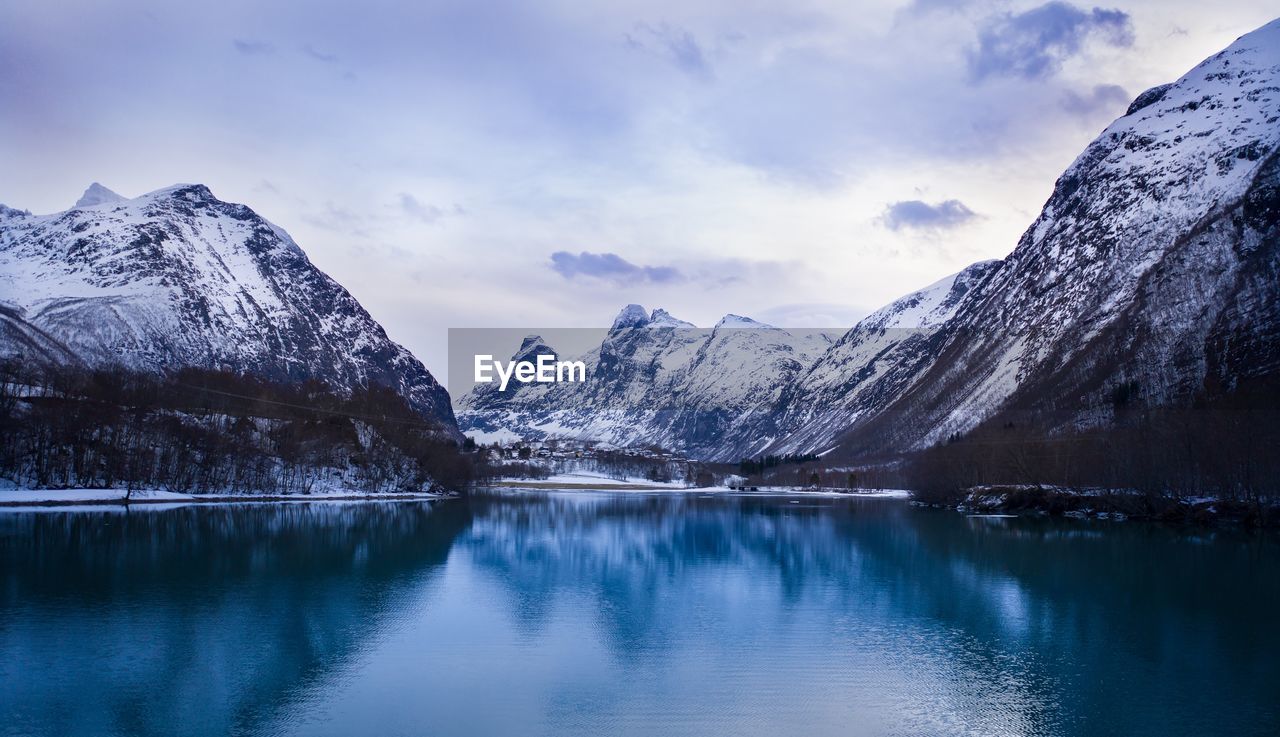 Scenic view of lake by snowcapped mountains against sky