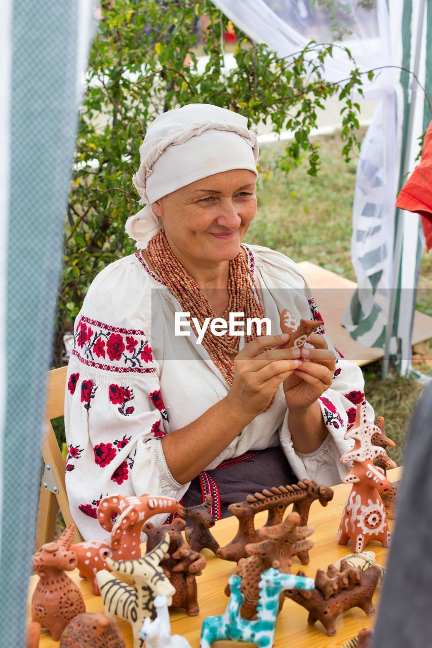 WOMAN HOLDING A SMILING WHILE STANDING OUTDOORS