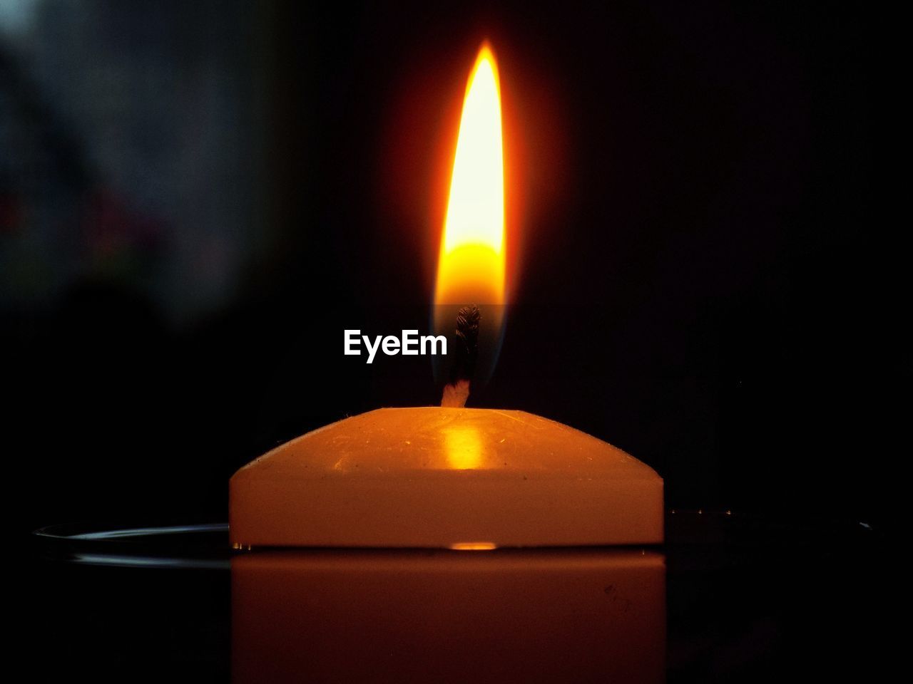 Close-up of lit candle in darkroom