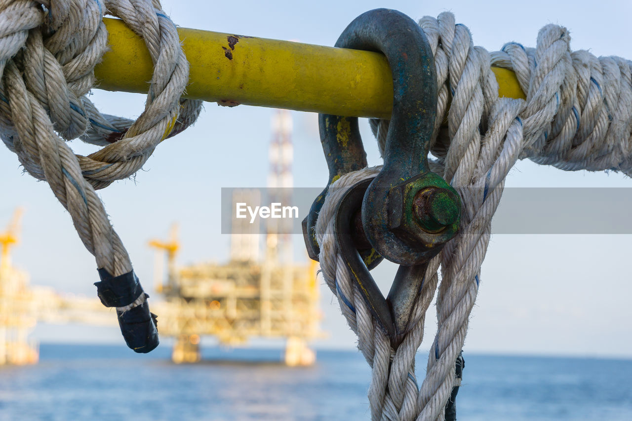 CLOSE-UP OF ROPE TIED TO WOODEN POST IN SEA