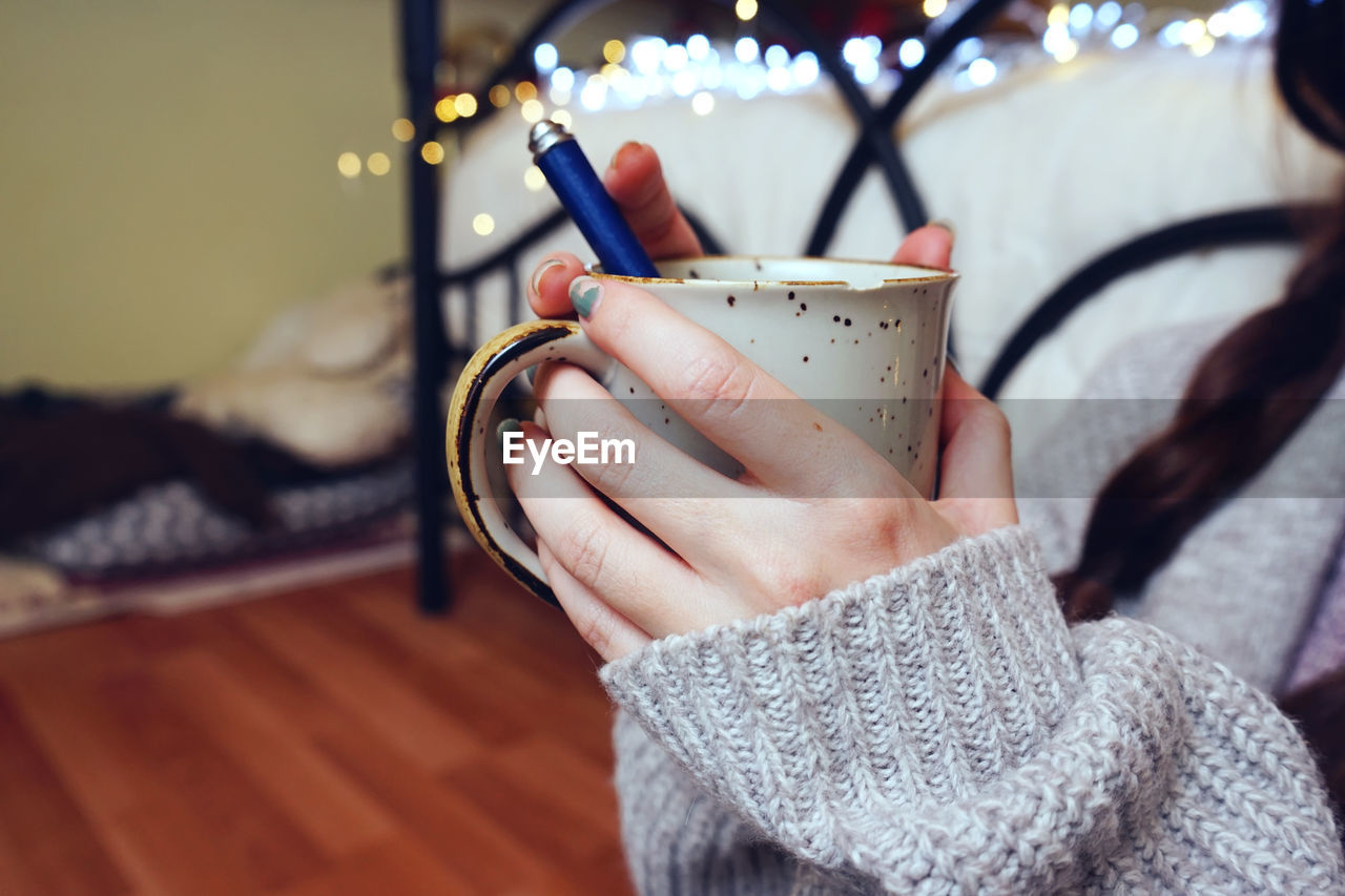 Close-up of hand holding coffee cup at home