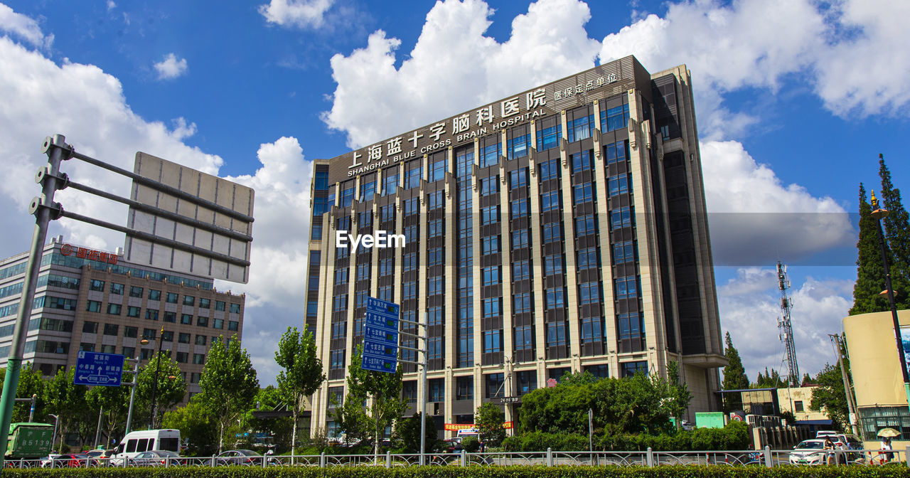 LOW ANGLE VIEW OF BUILDINGS AND TREES AGAINST SKY