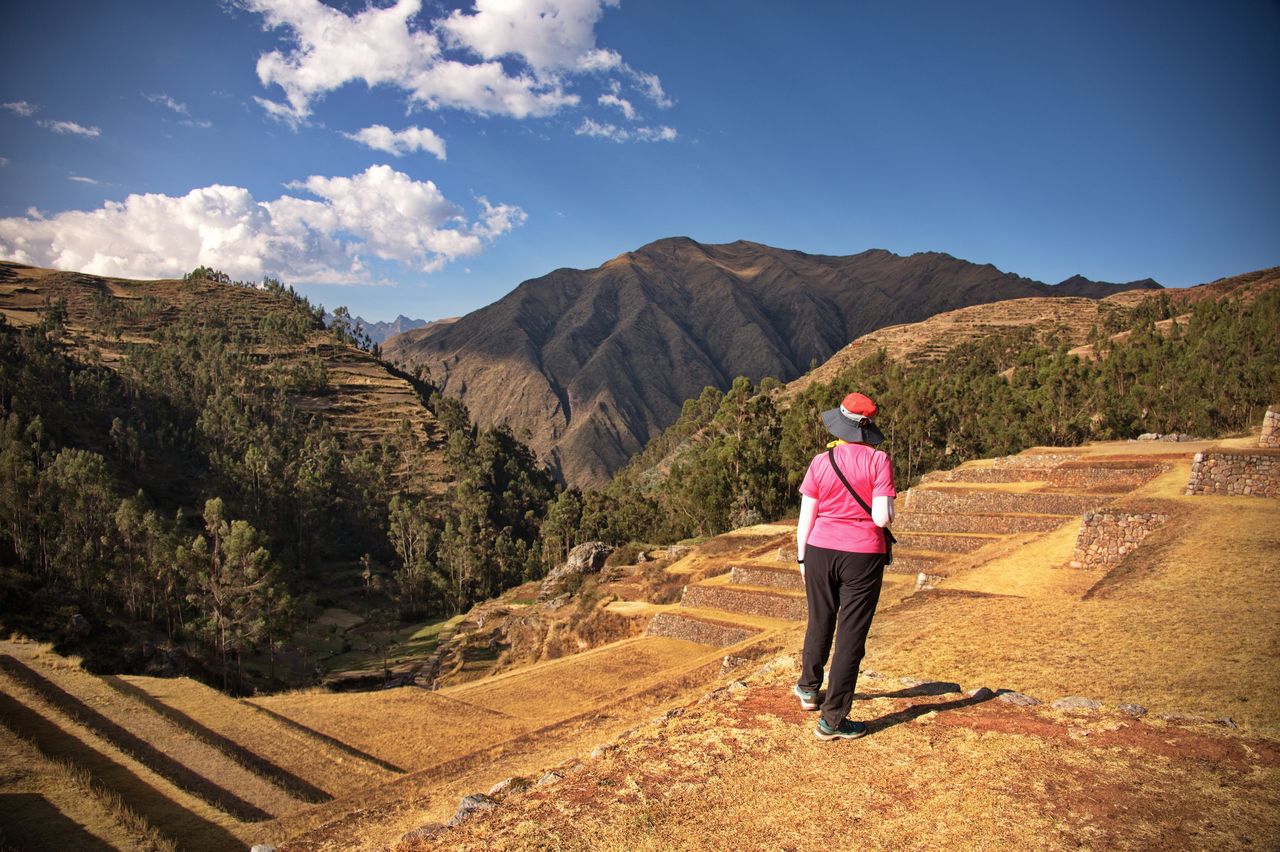 Rear view of the woman standing on the archaeological site in the beginning of inca trail