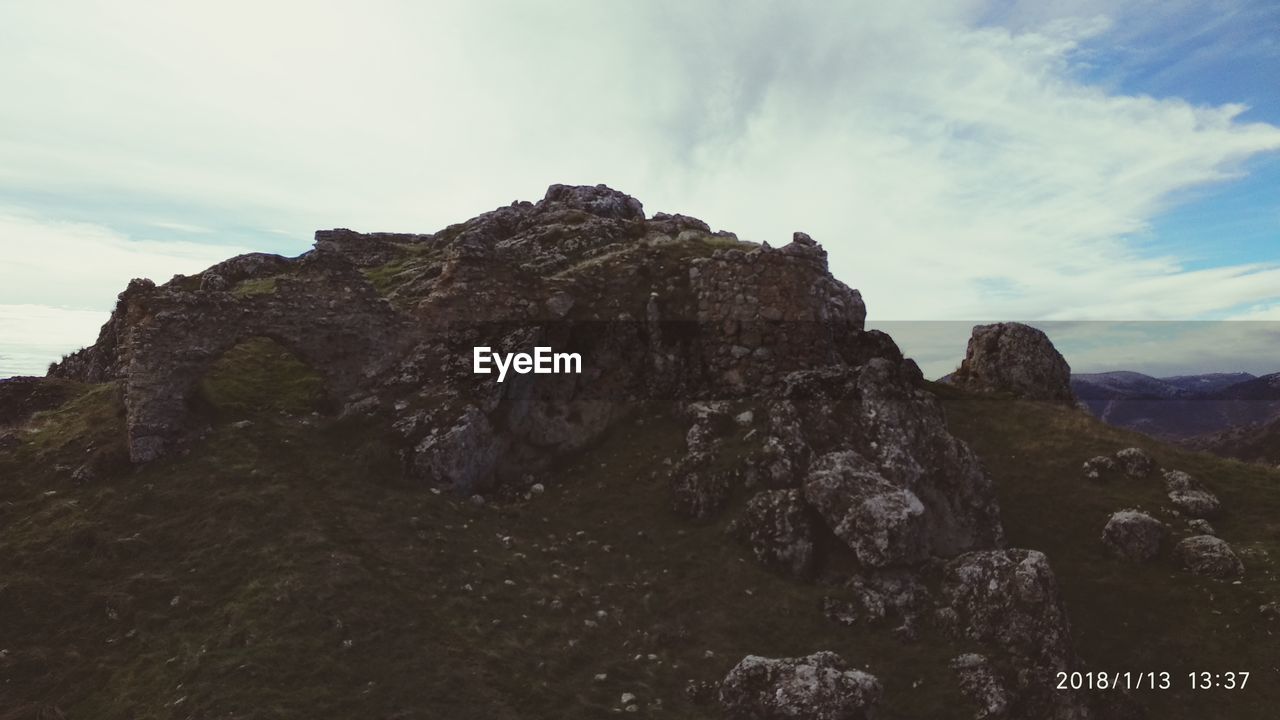 SCENIC VIEW OF CLIFF BY MOUNTAIN AGAINST SKY