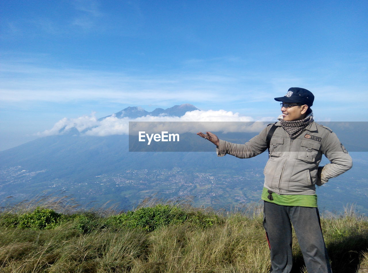 Optical illusion of man holding cloud while standing on mountain