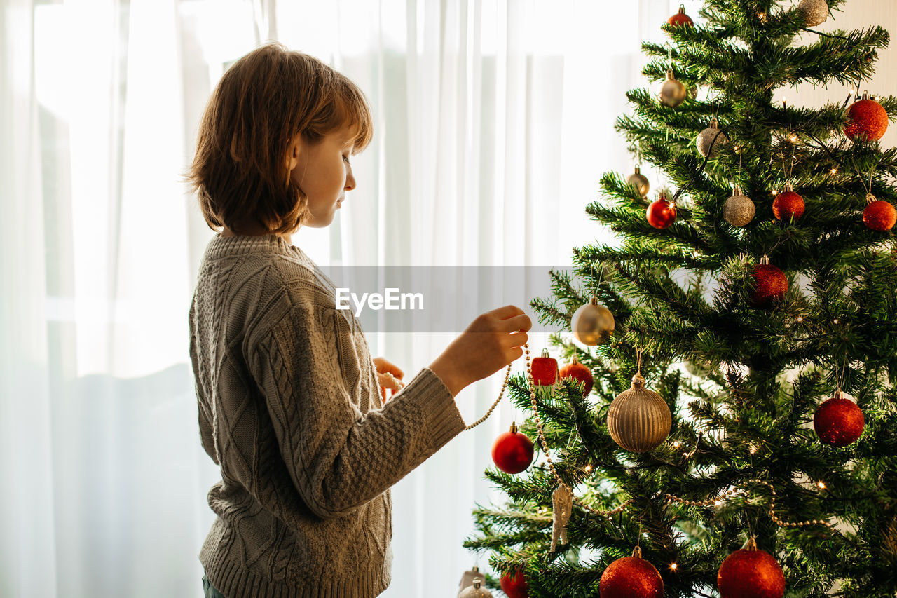 The girl decorates the christmas tree for the holiday. preparing for christmas and new year. 