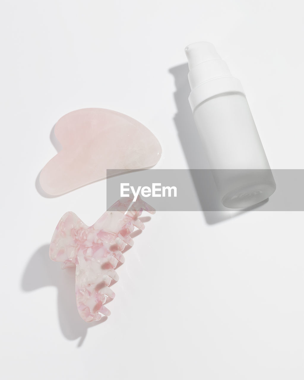 Gua sha scrapes from rose quartz, hair claws clip and moisturizing serum. beauty concept.