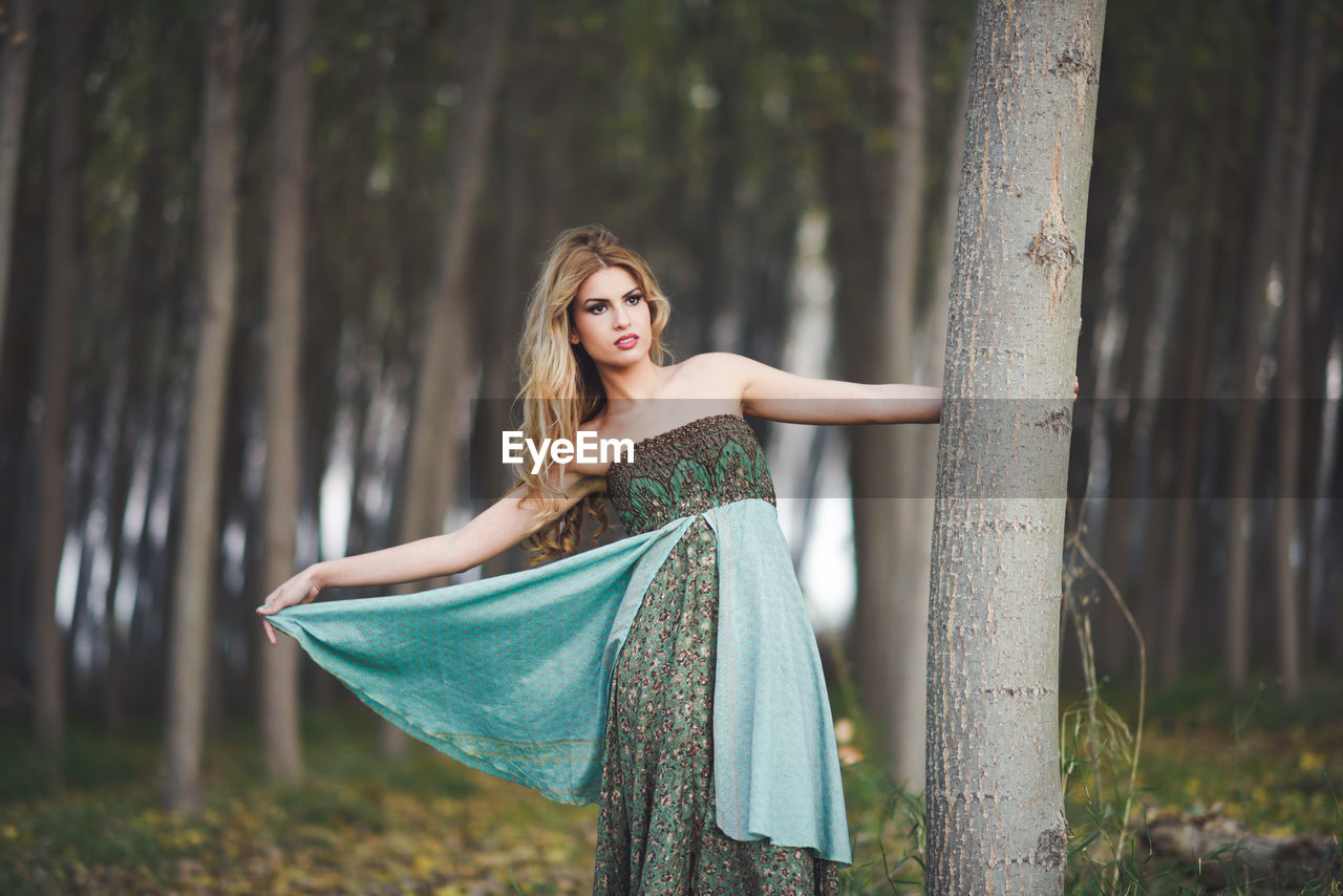 Young woman looking away while standing in forest