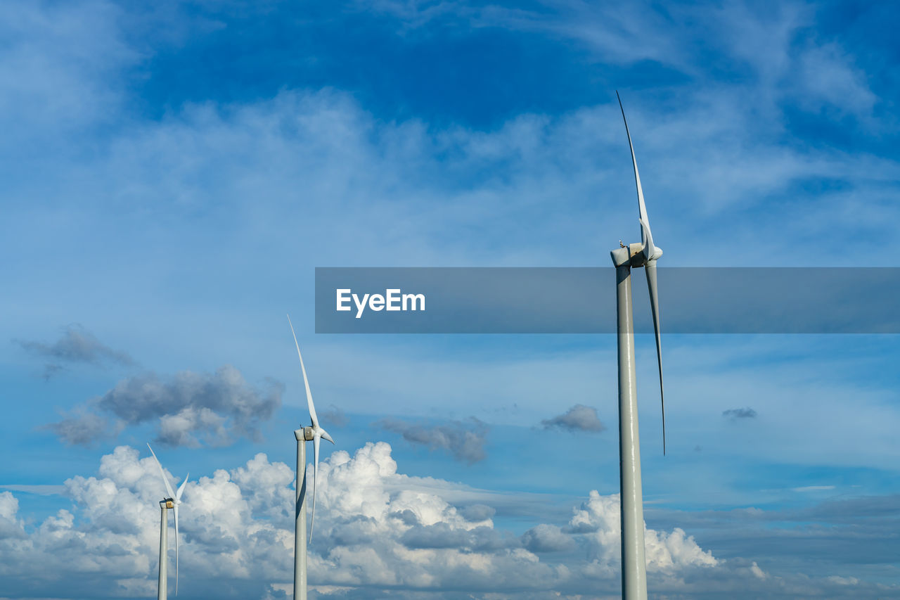 Close-up wind turbines or wind energy converter in sunny day with blue sky and white clouds