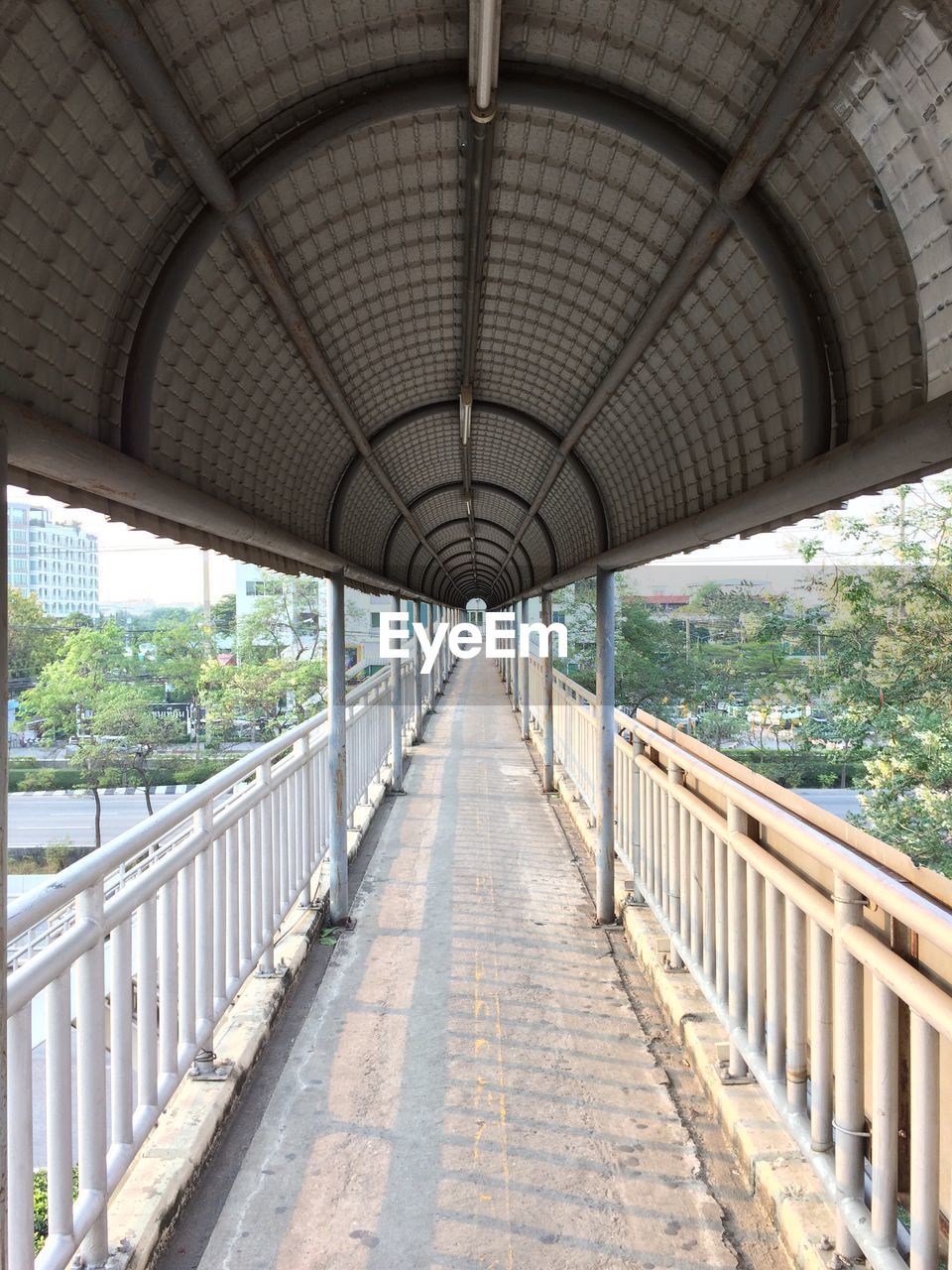 Empty elevated walkway in city during sunny day