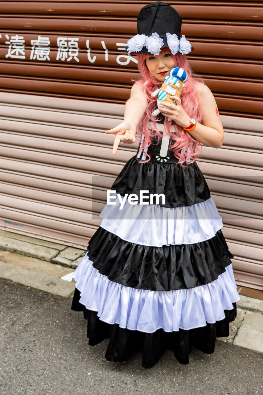 HIGH ANGLE VIEW OF GIRL HOLDING UMBRELLA STANDING AGAINST WALL