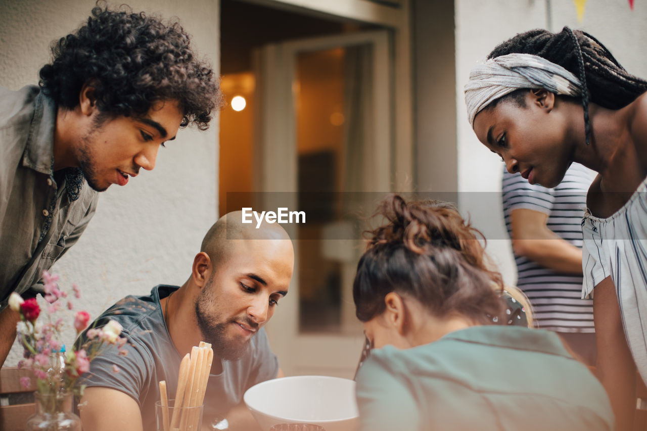 Curious multi-ethnic male and female friends looking down during dinner party