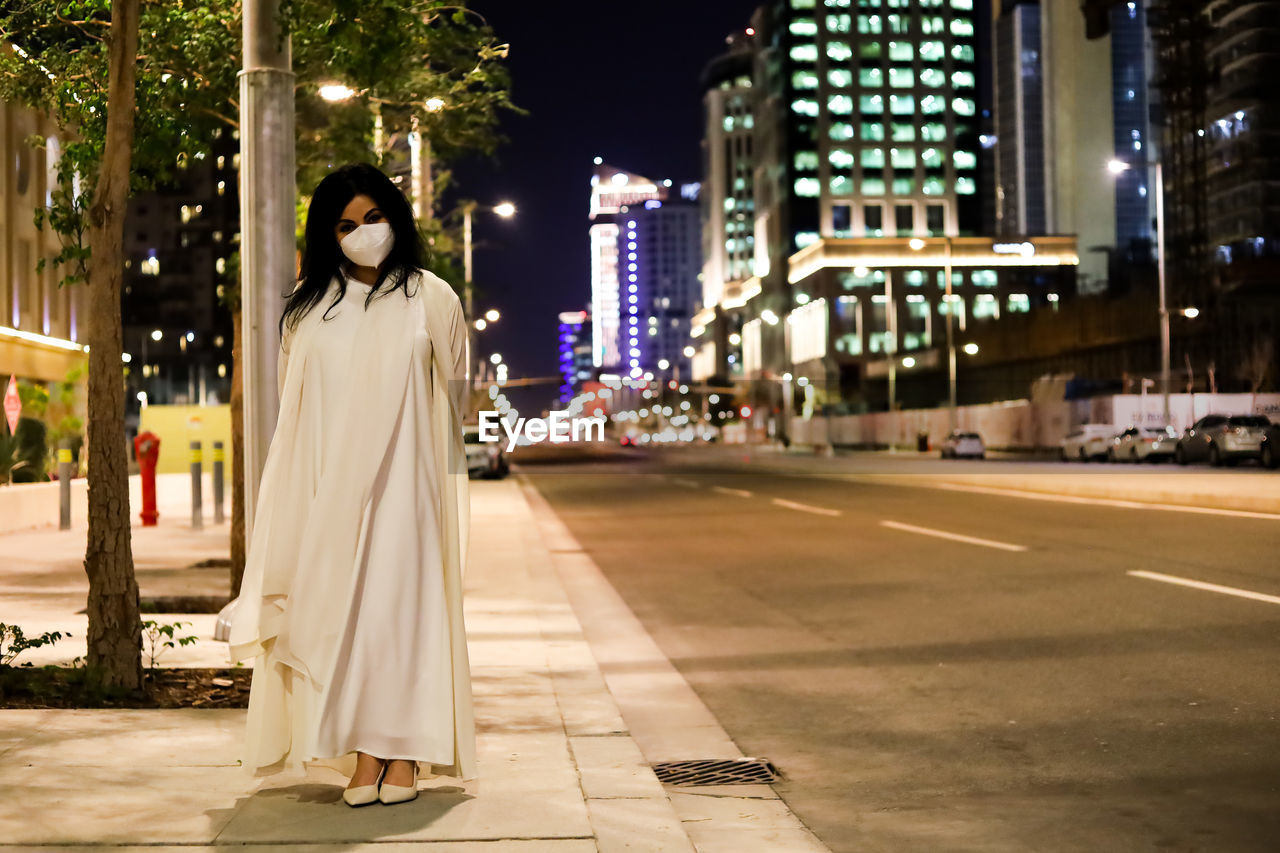 Portrait of woman standing on street in city at night