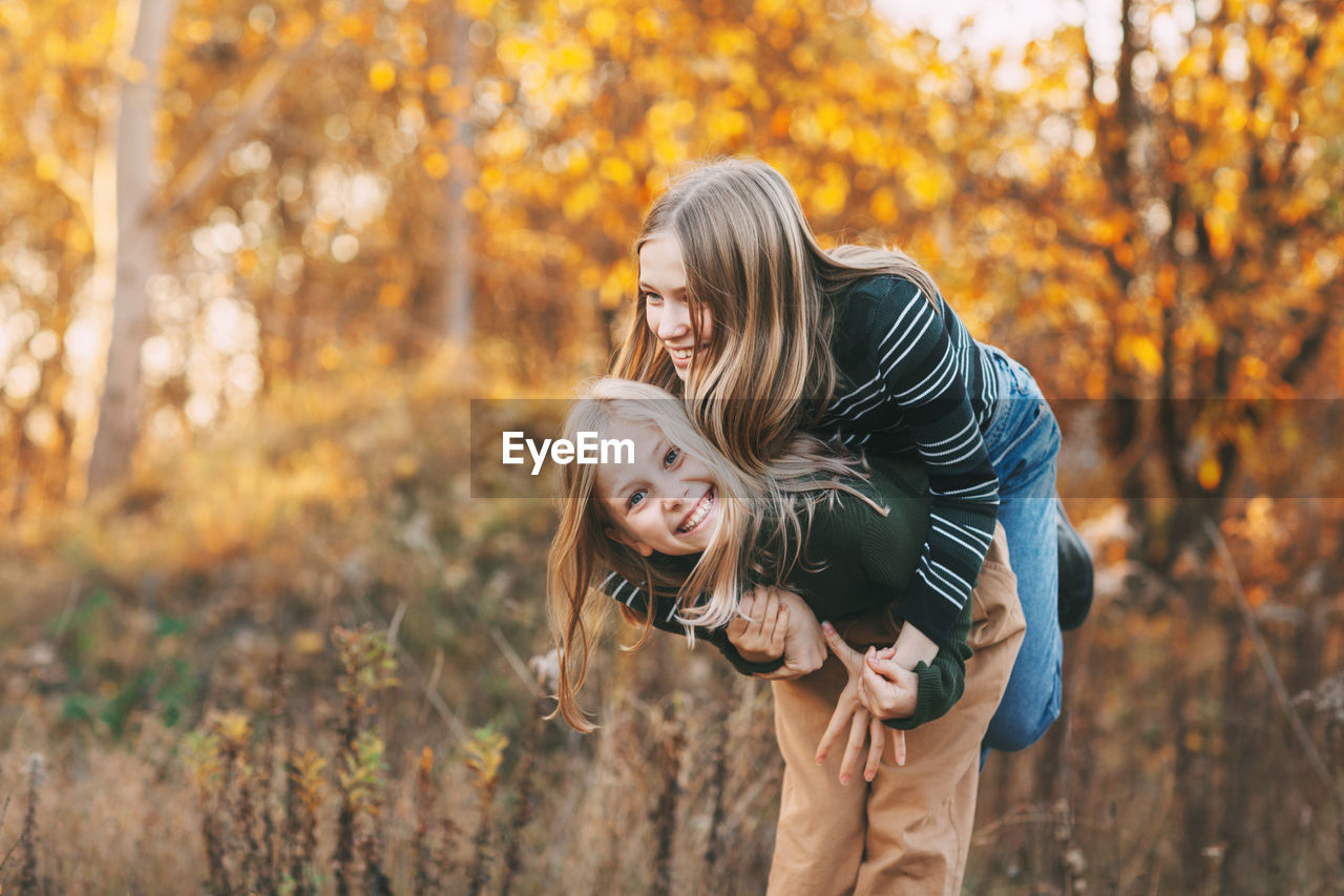 Little girls sisters laughing, having fun and playing in the fall in nature outdoors 