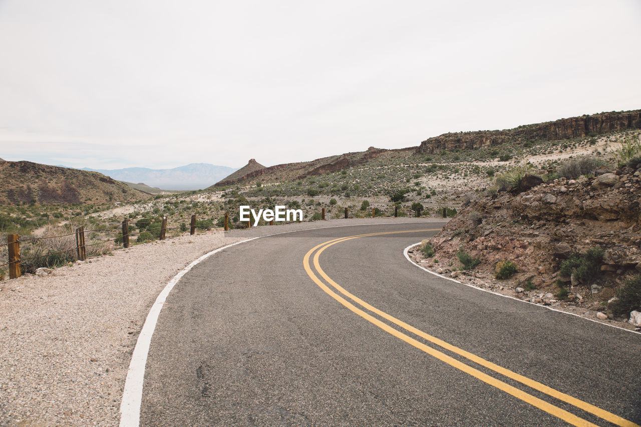 EMPTY ROAD BY MOUNTAINS AGAINST SKY