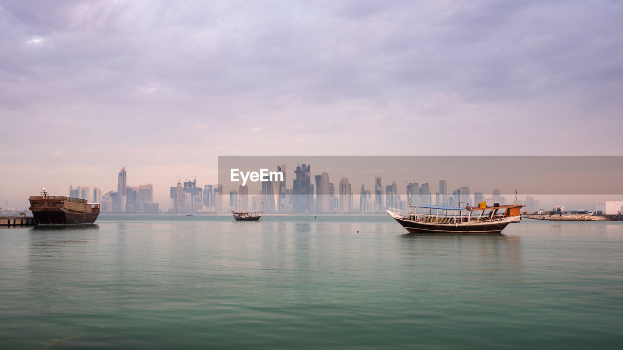 Boats in sea against sky in city