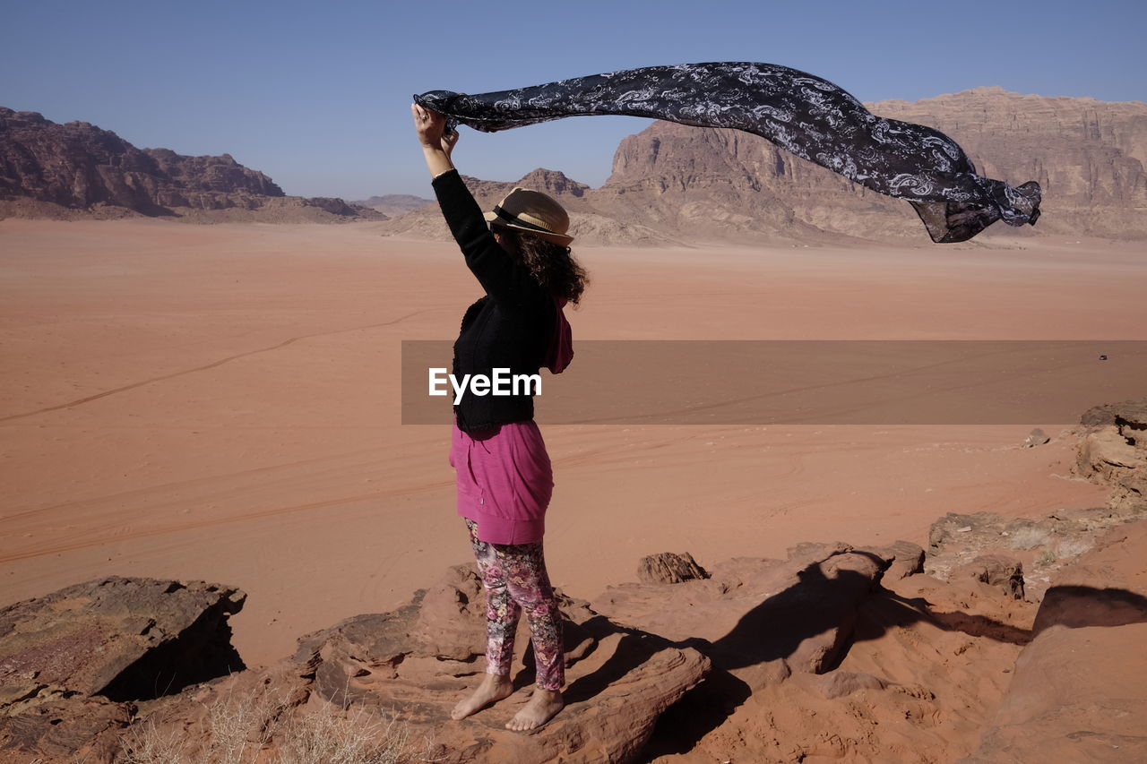 Full length of woman holding sarong in desert