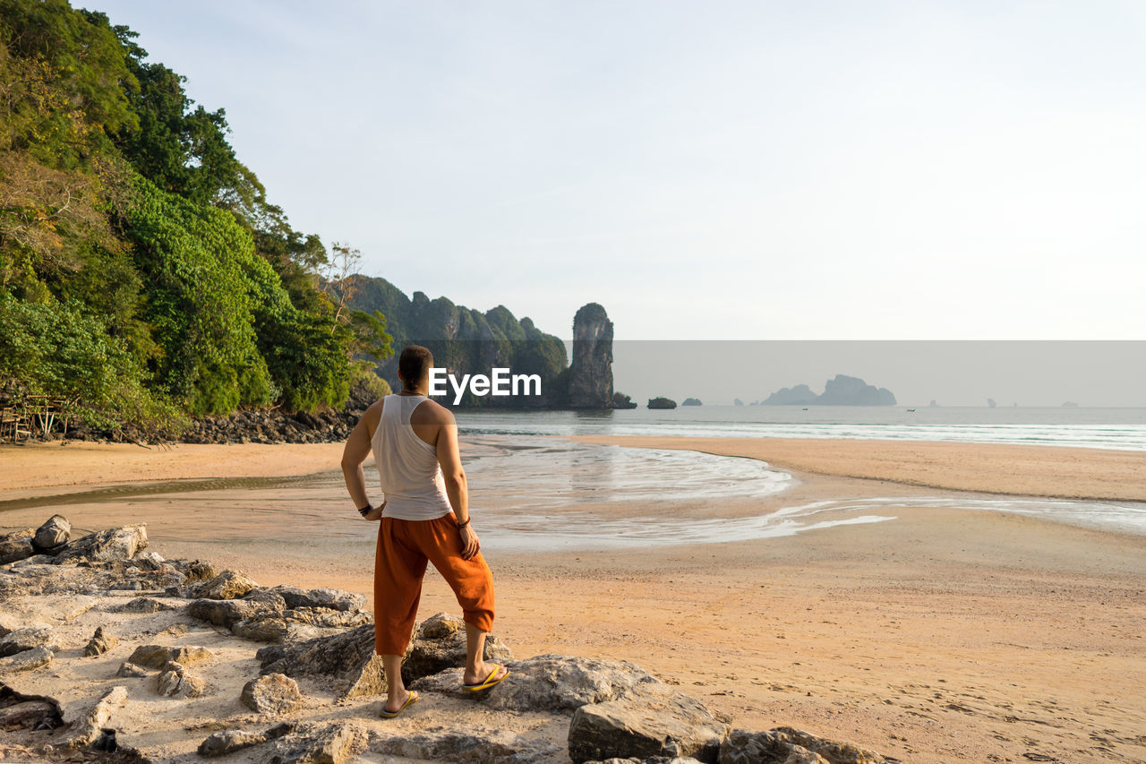 Rear view of ma looking at sea while standing on rock