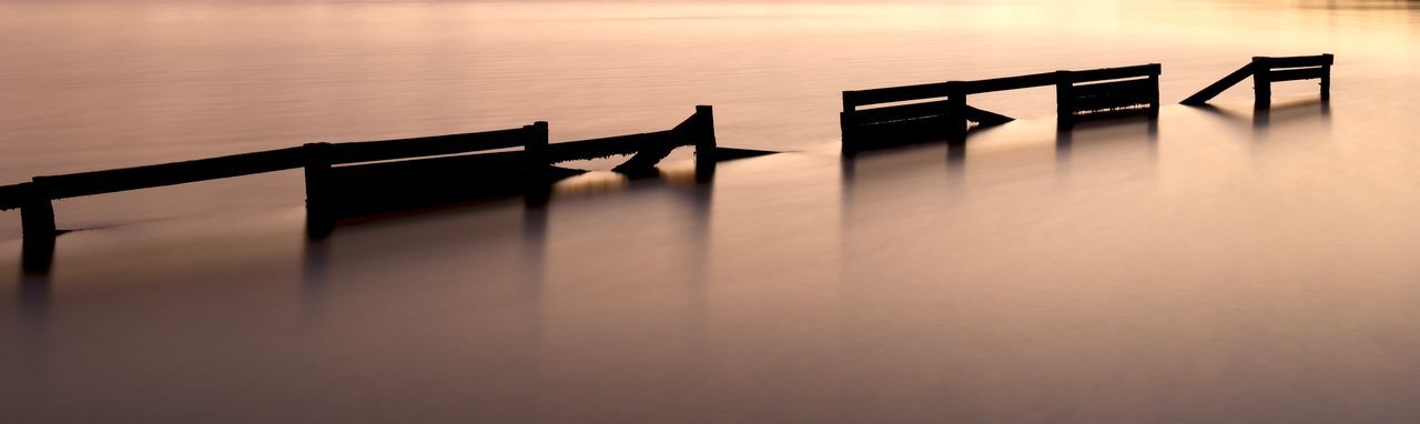 SILHOUETTE WOODEN TABLE ON SEA AGAINST SKY AT SUNSET