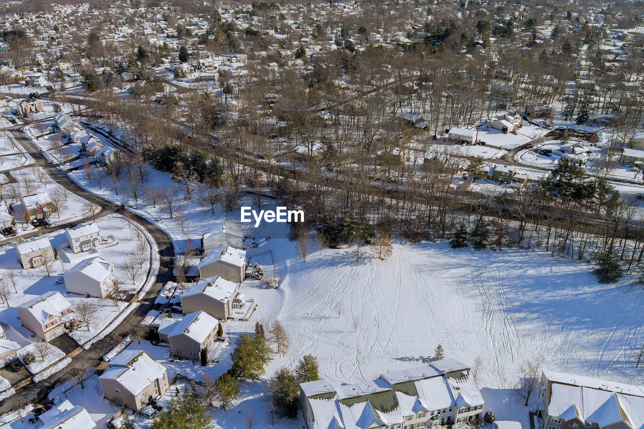 HIGH ANGLE VIEW OF SNOW COVERED HOUSES AND TREES