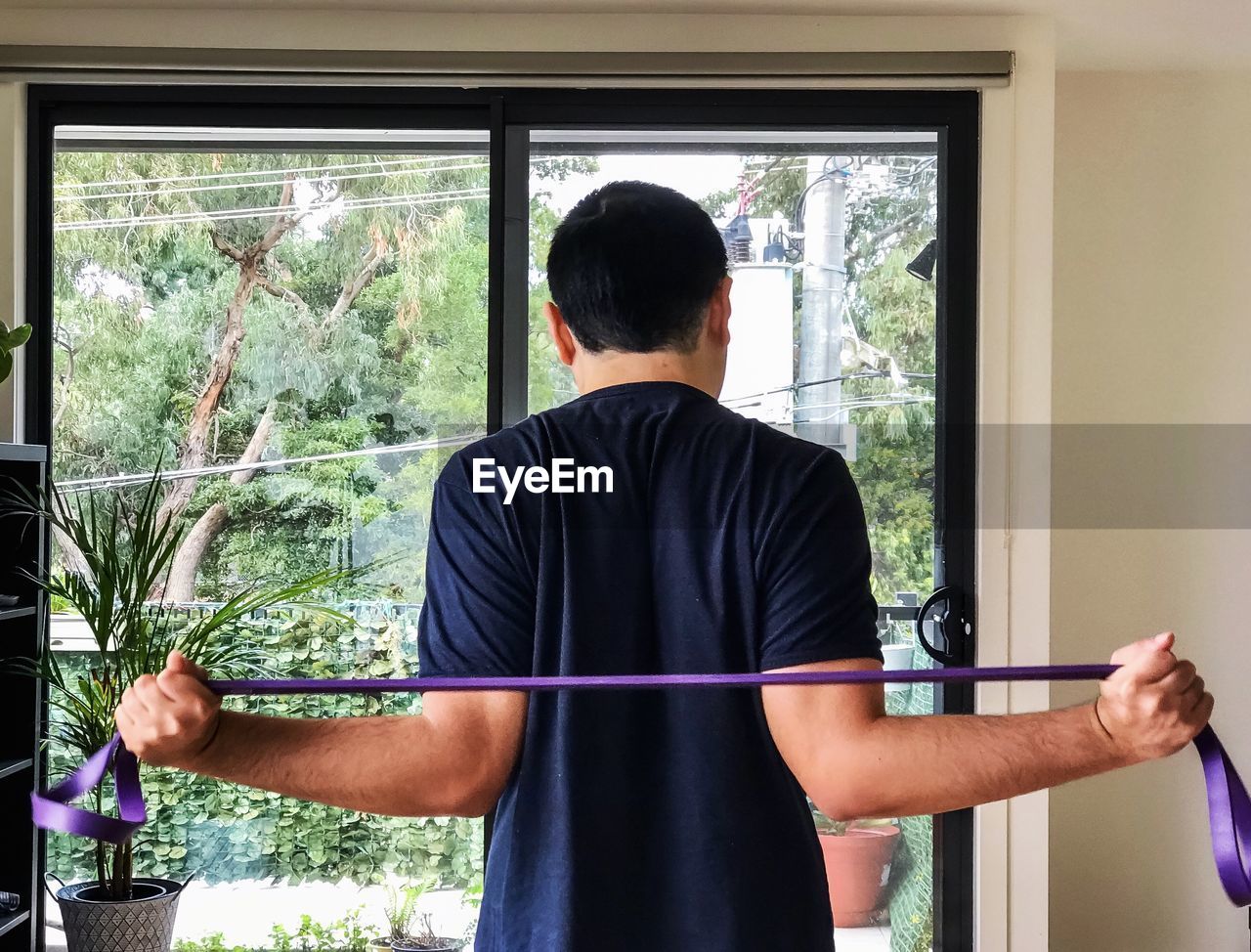 Rear view of man doing resistance band exercises.