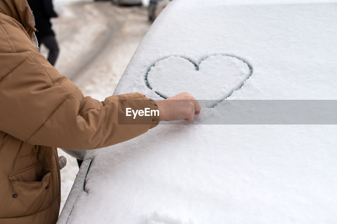 Drawing of a heart in the snow, the snow lies on the car