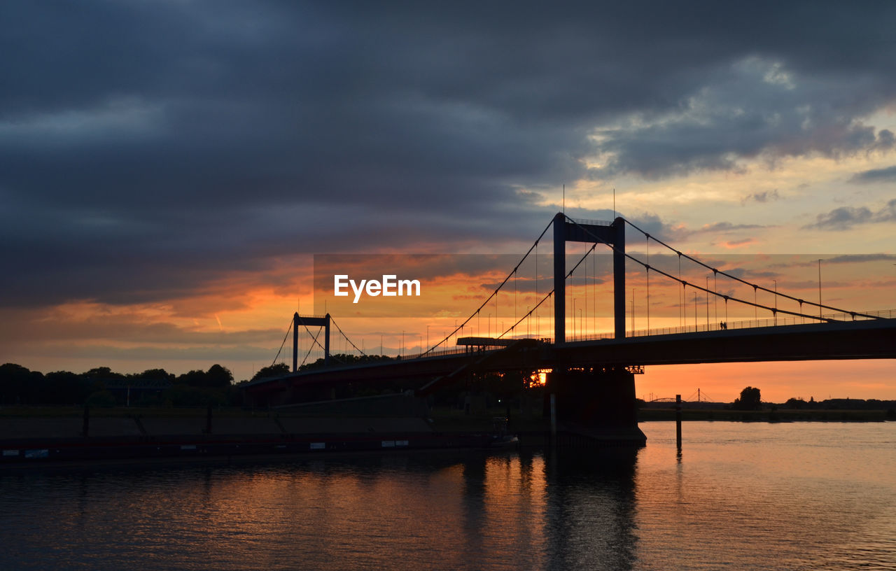 Silhouette bridge over river rhine against sky during sunset