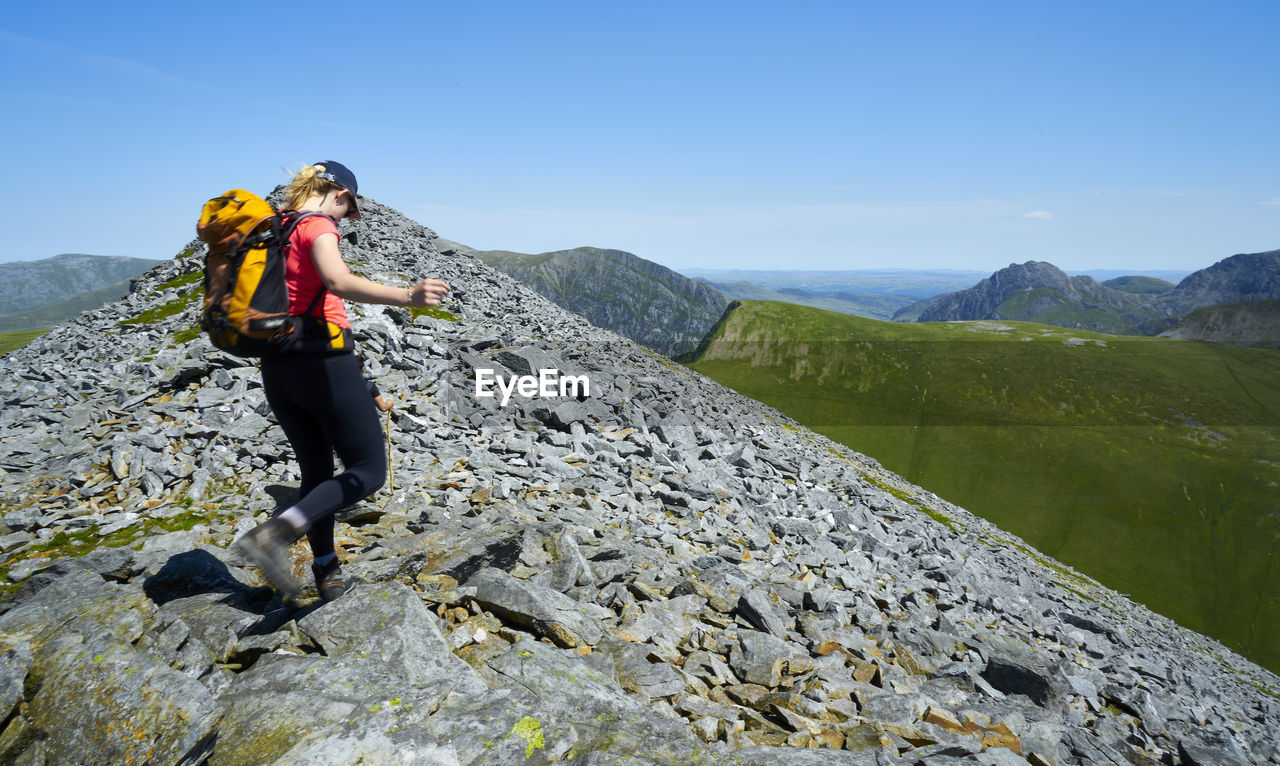 Woman walking on mountain against sky