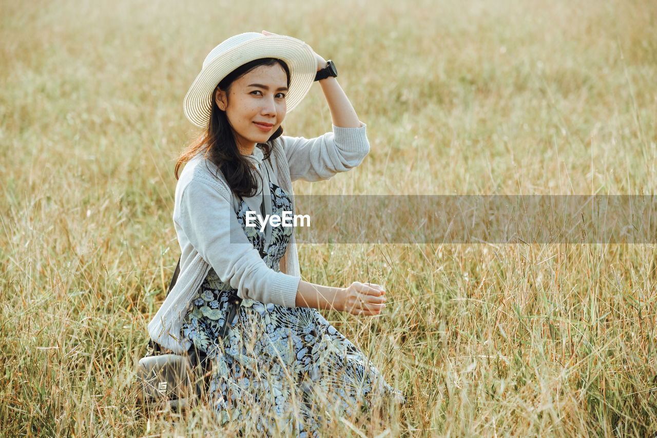 Portrait of smiling mid adult woman relaxing on grassy field